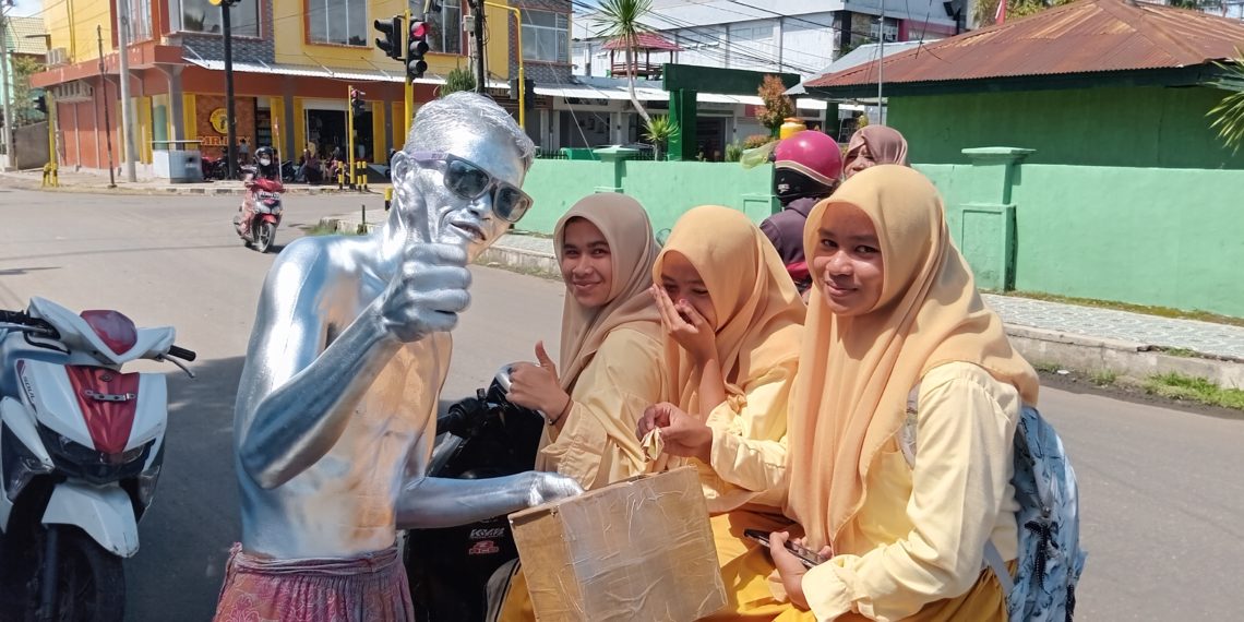 📷 Pelajar ini sengaja berhenti hanya untuk berpose dan menyerahkan uang buat manusia perak. Pelajar lainnya yang kebetulan lewat disitu pasti menyempatkan menghampiri Yono dan mengajak foto selfie. (my).