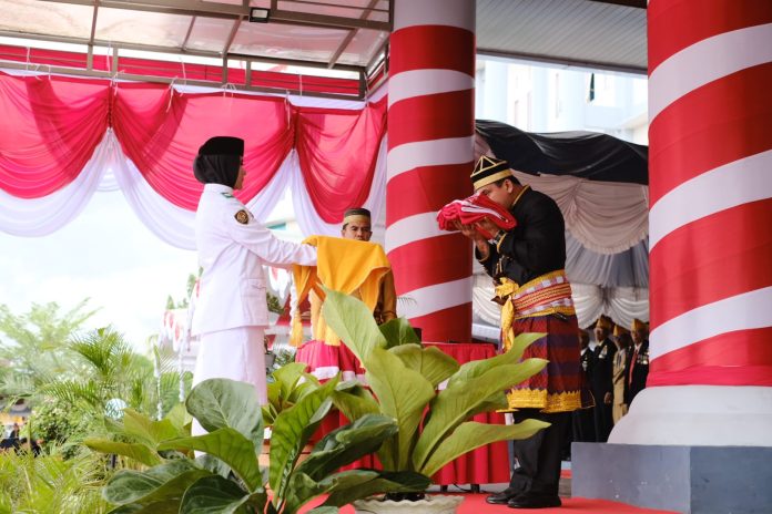 📷 Petugas pembawa Baki sedang menerima Bendera dari Inspektur Upacara di atas panggung kehormatan. (Humas Setda).